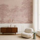 A styled interior room featuring a large wall mural with a muted sepia landscape scene, white wainscoting, a wooden sideboard, a cream curved accent chair, and a small mint green side table.